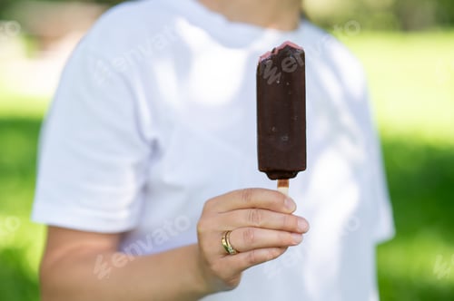 Preview: Woman holding chocolate ice cream on stick close up