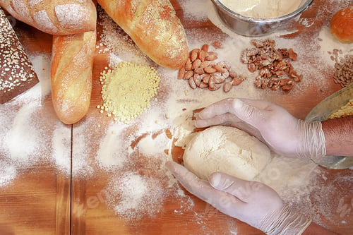 Preview: Closeup of the hands in gloves baking bread with almonds and walnuts.