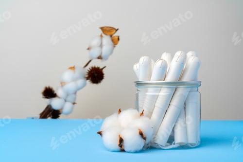 Preview: Female medical tampons and cotton flower on blue paper background