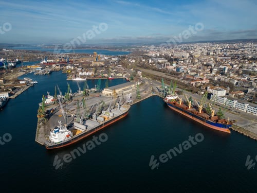Preview: Aerial view of a bulk carrier ship loaded with grain is docked at a busy port, with workers and