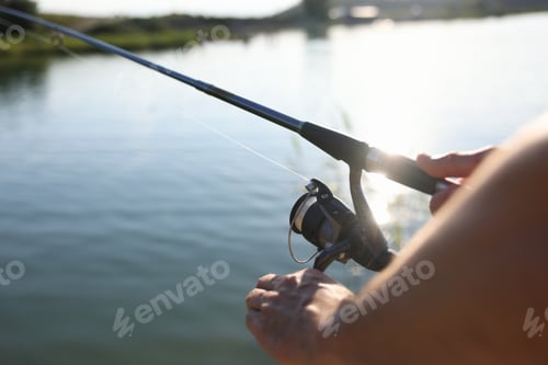Preview: Fisherman with rod fishing near lake at summer, closeup