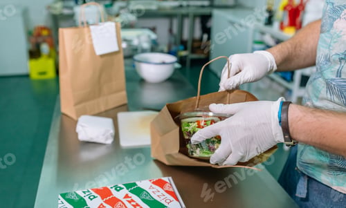 Preview: Unrecognizable cook packing a takeaway order