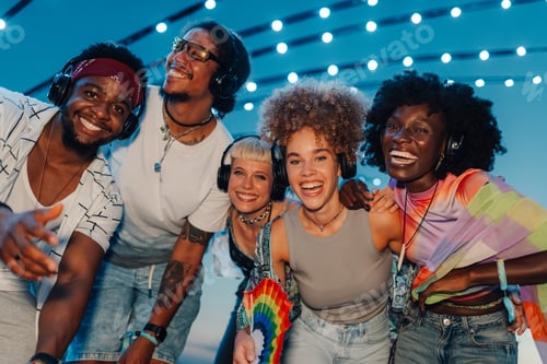 Preview: Happy friends enjoying silent disco with headphones at night