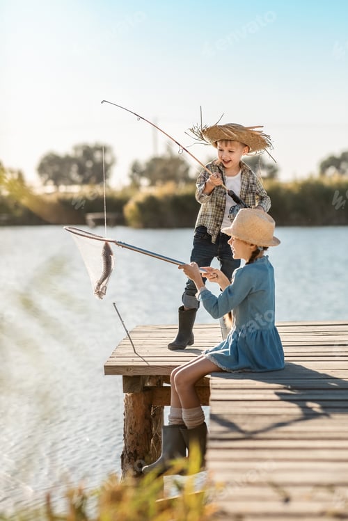 Preview: a boy and a girl have fun fishing on the lake from a wooden pier on a sunny day
