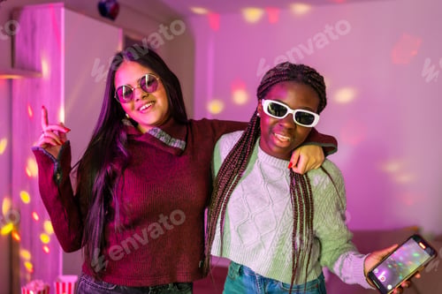 Preview: Two cheerful teenagers having fun at home party with disco lights