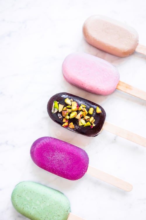 Preview: Flat lay with colorful popsicles on white marble table
