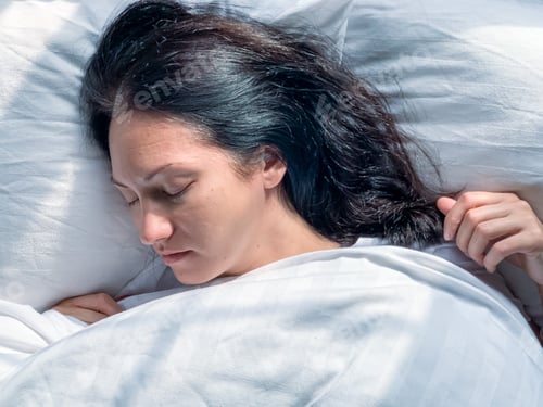 Preview: Young millennial candid woman sleeps at home on a white striped bedsheets. Early morning atmosphere