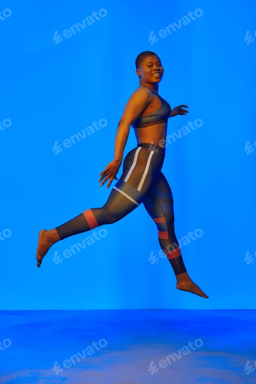 Preview: Happy african american woman wearing sportive clothes showing plus size hips. Body positive concept