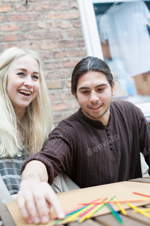 Preview: Happy couple playing Mikado at cafe backyard
