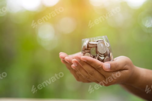 Preview: Hand with coins on bokeh background .save money concept