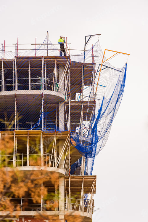 Preview: Construction worker on top of a building under construction directing a crane.