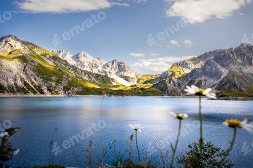 Preview: Tranquil Lunersee lake surrounded by lush green grass and jagged mountains in Austria