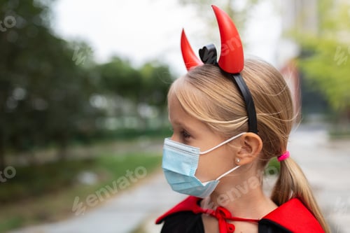 Preview: Happy kid in evil costume celebrating Halloween 2021 during coronavirus covid-19 pandemic