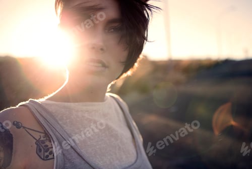Preview: A young woman standing outdoors at sunset.