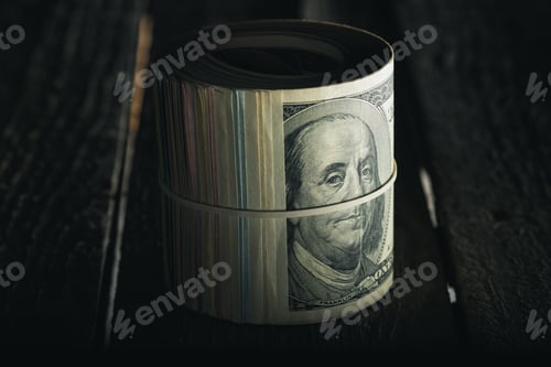 Preview: close up of dollar banknotes in roll with rubber band