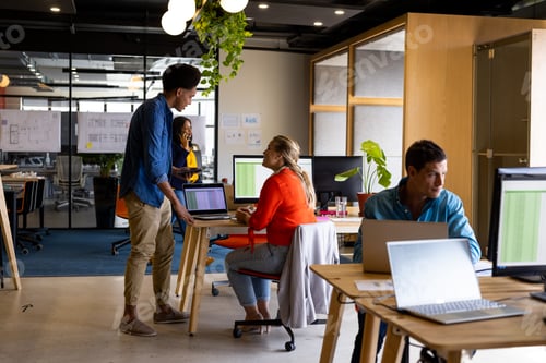 Preview: Diverse male and female colleagues in discussion at desk in office