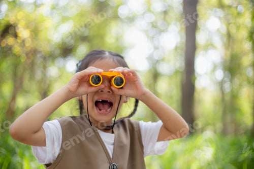 Preview: Happy Little Asian girls looking ahead and smiling child with the binoculars in the park.