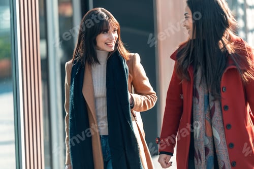 Preview: Two beautiful friends talking and having fun while walking on the city street with shopping bag.