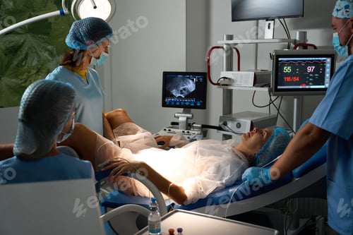 Preview: Hospital staff doing ultrasound examination of pregnant patient on medical couch