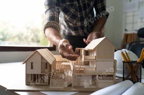 Preview: architect working and discussing about an architecture model together with shop drawing paper on