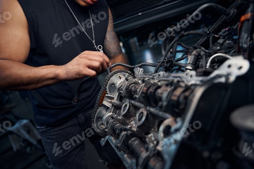 Preview: African-American auto-mechanic engaging in car engine repairing