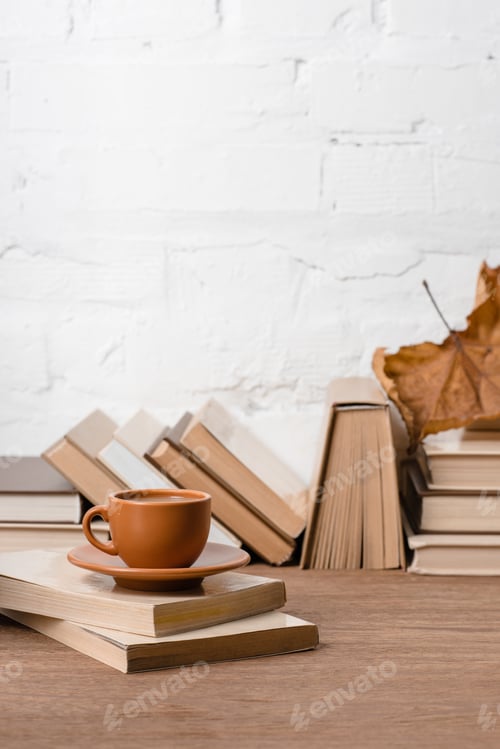 Preview: books, cup of coffee and dry autumn leaf on wooden table