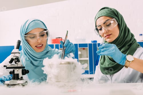 Preview: female muslim scientists in hijab experimenting with microscope and dry ice in chemical laboratory
