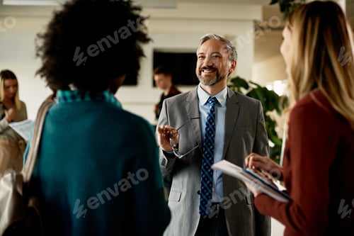 Preview: Happy mature teacher communicating with students in hallway at the university.