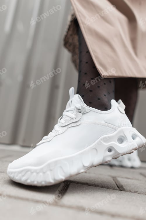 Preview: Women's stylish white sports sneaker on a woman's foot in the city