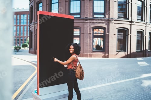 Preview: African American glad female traveling using billboard in urban street