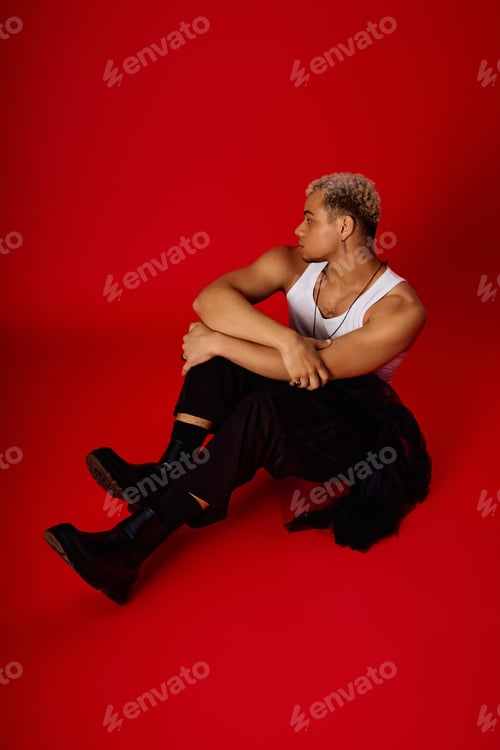 Preview: Young African American man embodies style and confidence in vibrant red studio