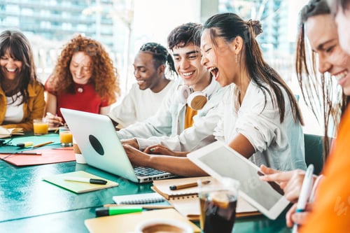 Preview: Multiracial university students sitting together at table with books and laptop
