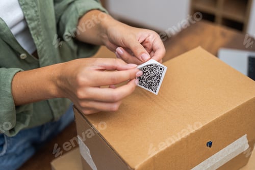Preview: close up woman attaches qr code sticker to cardboard parcel to return and receive a refund.