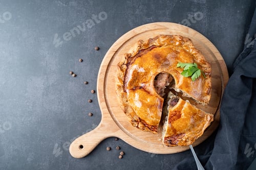 Preview: Homemade meat pie with greenery on wooden cutting board on dark table