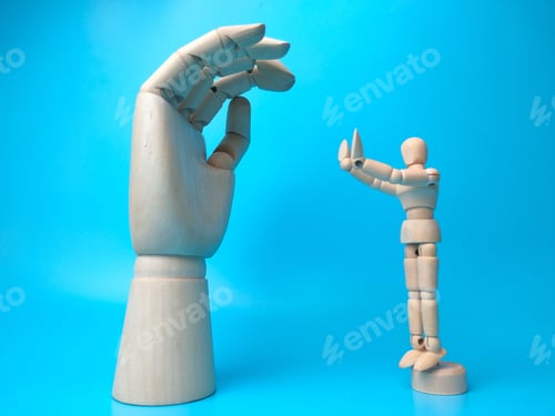 Preview: Wooden mannequin makes a stopping pose in front of a wooden hand against a blue background