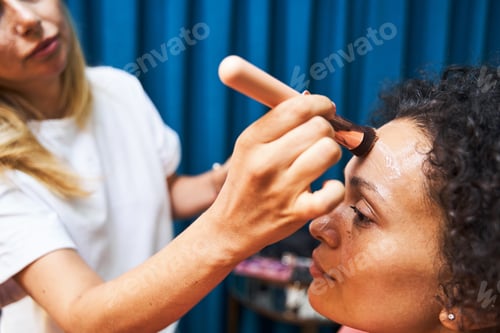 Preview: Focused photo on stylist putting base on face