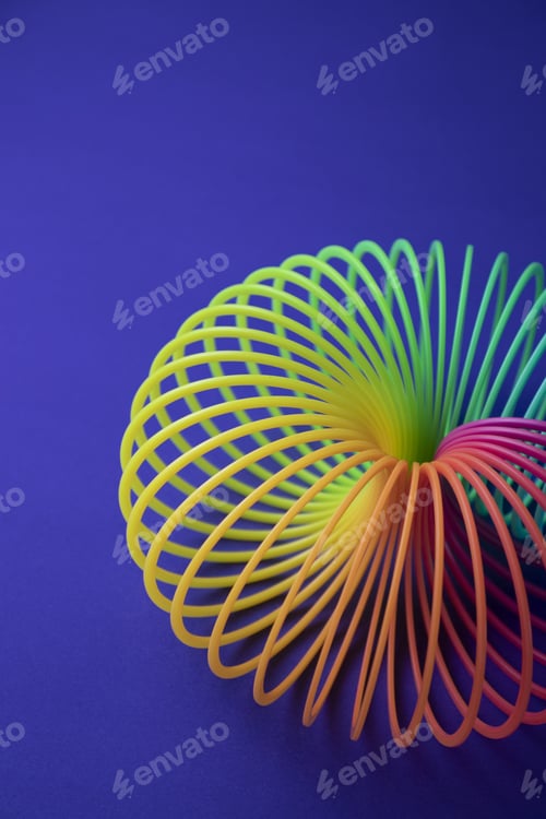 Preview: Plastic colorful rainbow magic spring toy isolated on blue background with copy space