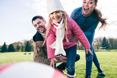 Preview: Happy family playing with ball on green meadow in park at sunny autumn day
