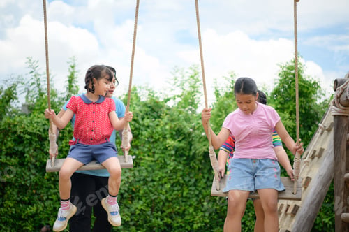 Preview: Childrens having fun swinging on a swing on a clear day