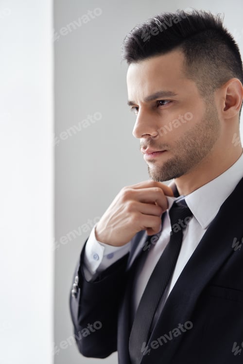 Preview: Confident Man Adjusting His Tie in Studio