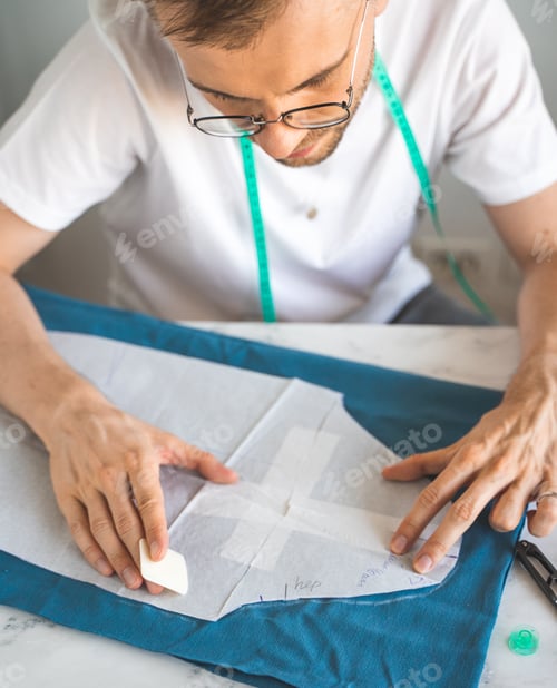 Preview: A self-taught seamster in white t-shirt and glasses works with fabric, pattern and chalk