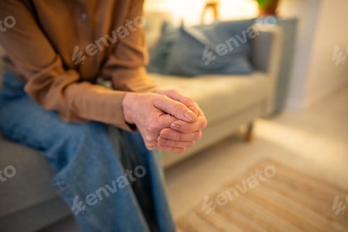Preview: Nervous unrecognizable woman sits on sofa with arms tightly crossed in therapy session counseling
