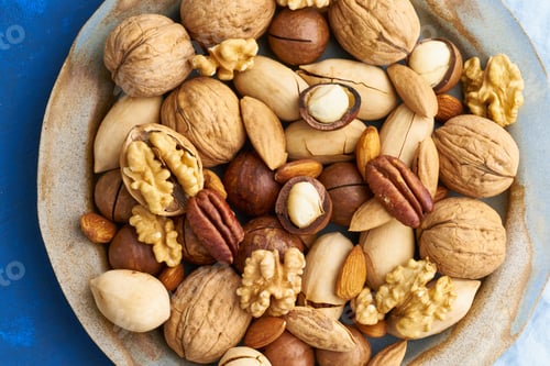 Preview: Classic blue in food. Mix of nuts on plate - walnut, almonds, pecans, macadamia