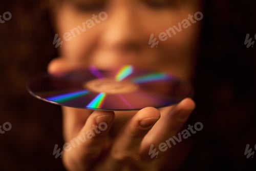 Preview: Caucasian Young Adult Woman Holding Compact Disc with Reflected Light