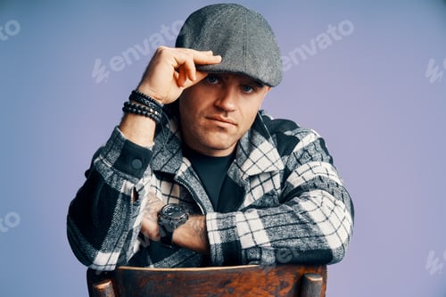 Preview: Stylish handsome man posing sitting on the chair on blue studio background