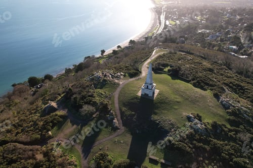 Preview: Aerial view of Killiney Hill with Obelisk and coastline in Dublin, Ireland under a clear sky.