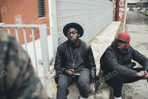 Preview: three african friends sitting outdoor using smartphone