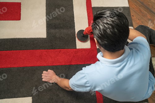 Preview: Top view of a laundry employee cleaning carpet with electric brush