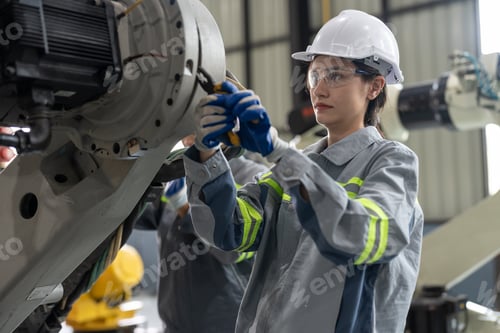 Preview: Female engineer checking and maintaining robot arms machine at factory