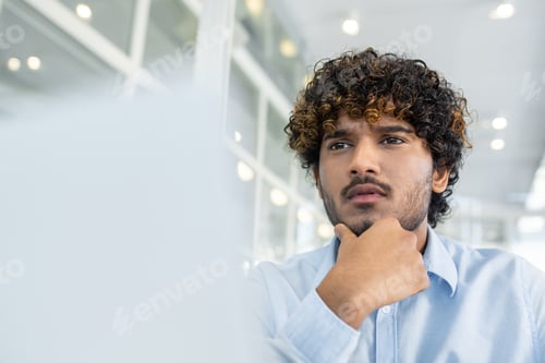 Preview: Young businessman deep in thought at modern office